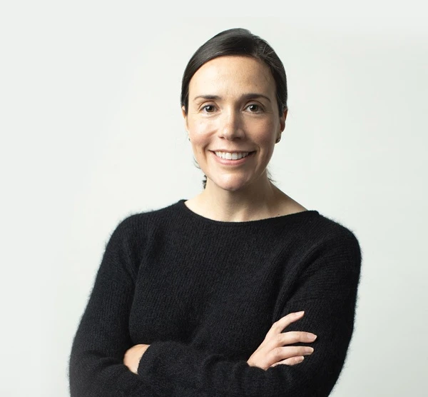 Martha Casey wearing a black sweater with her arms crossed and smiling.