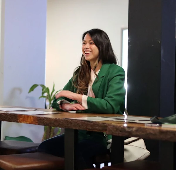 Two people talking and smiling while sitting around a desk.