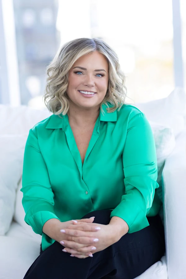 A blonde woman wearing a bright green blouse and smiling.