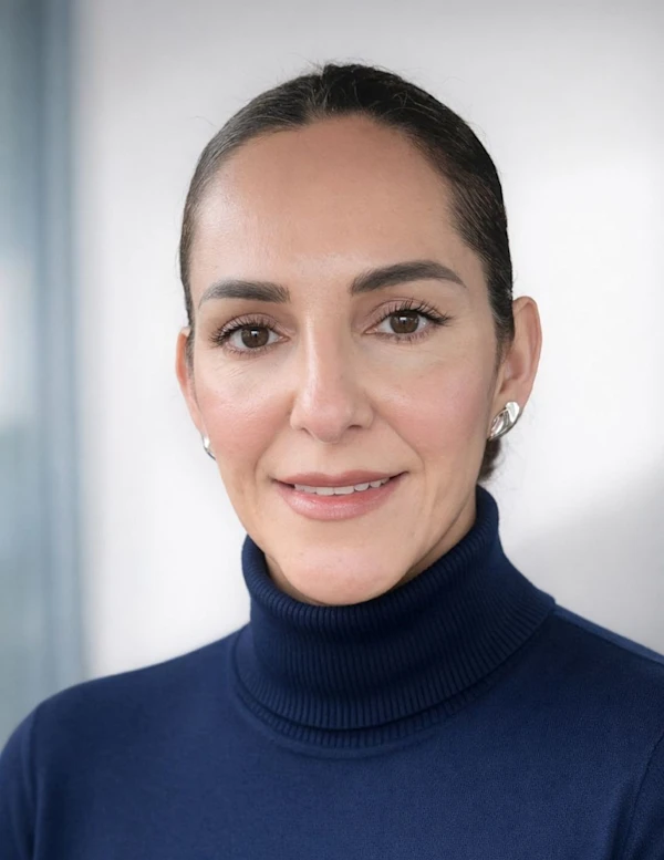 A woman wearing a blue turtleneck sweater smiling.