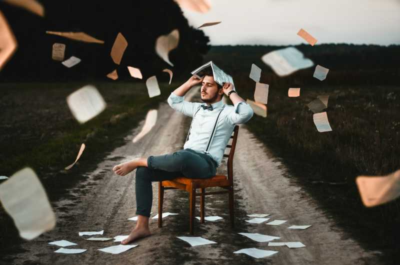 A man sitting on a chair surrounded with pages