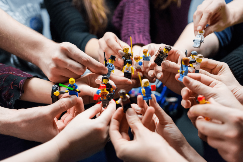 A group of people holding Lego people adorned with different characteristics. 