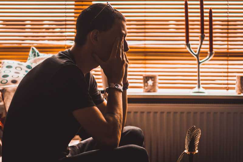 a man sitting on chair covering his eyes