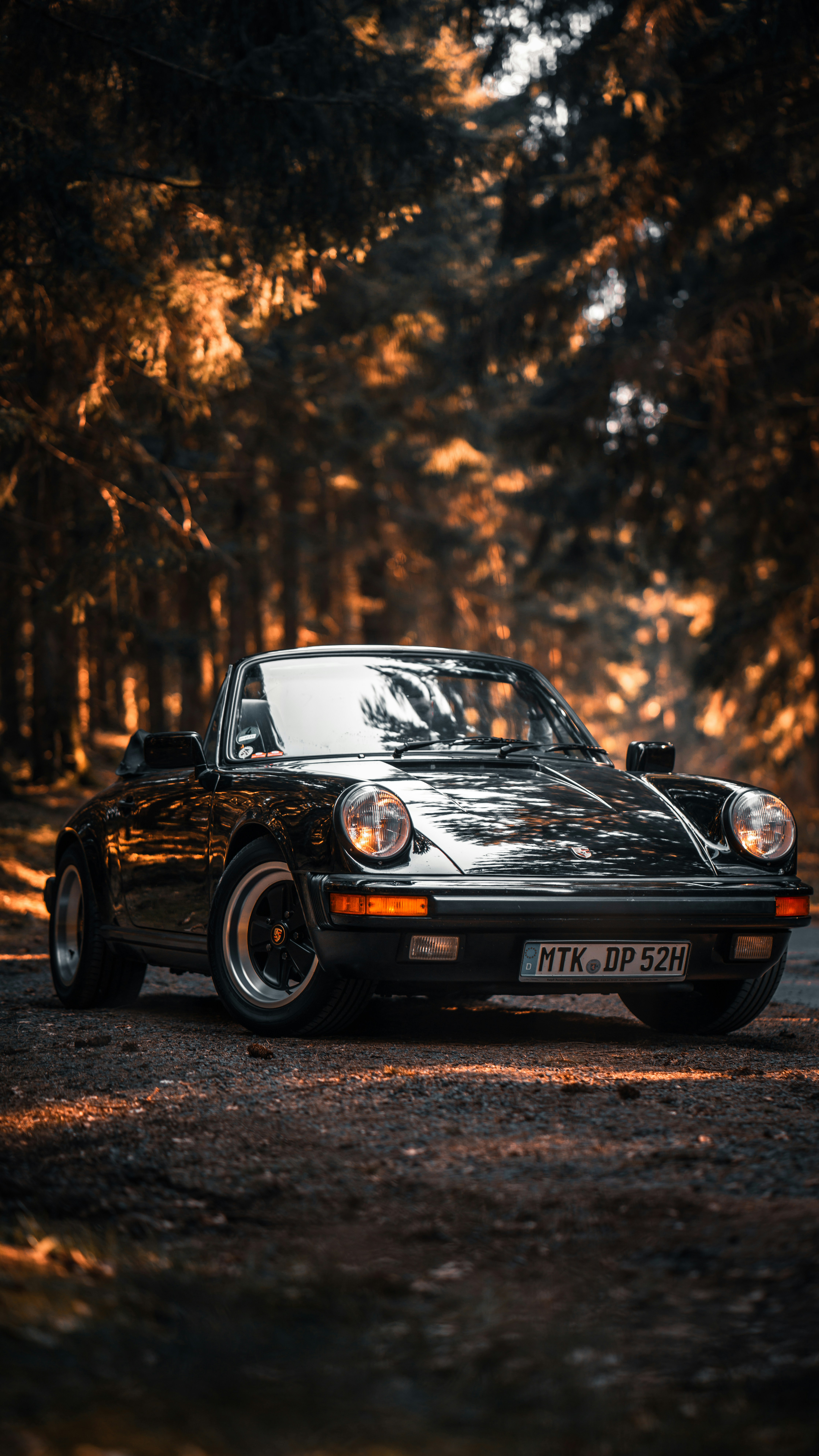 Classic black Porsche 911 Targa on a forest road at golden hour — evolution without losing character