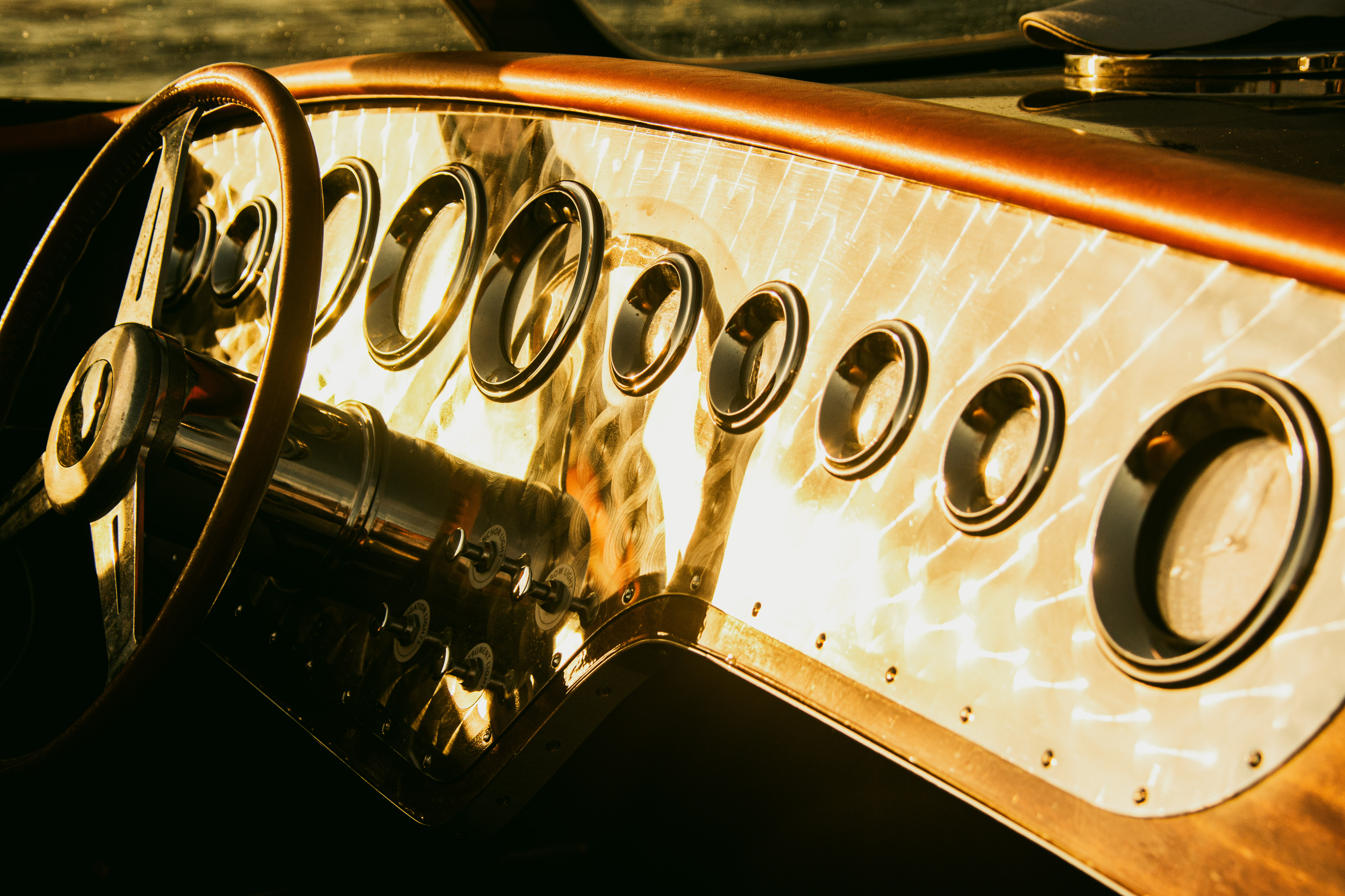 Polished J Craft dashboard gauges bathed in golden light with leather-wrapped steering wheel