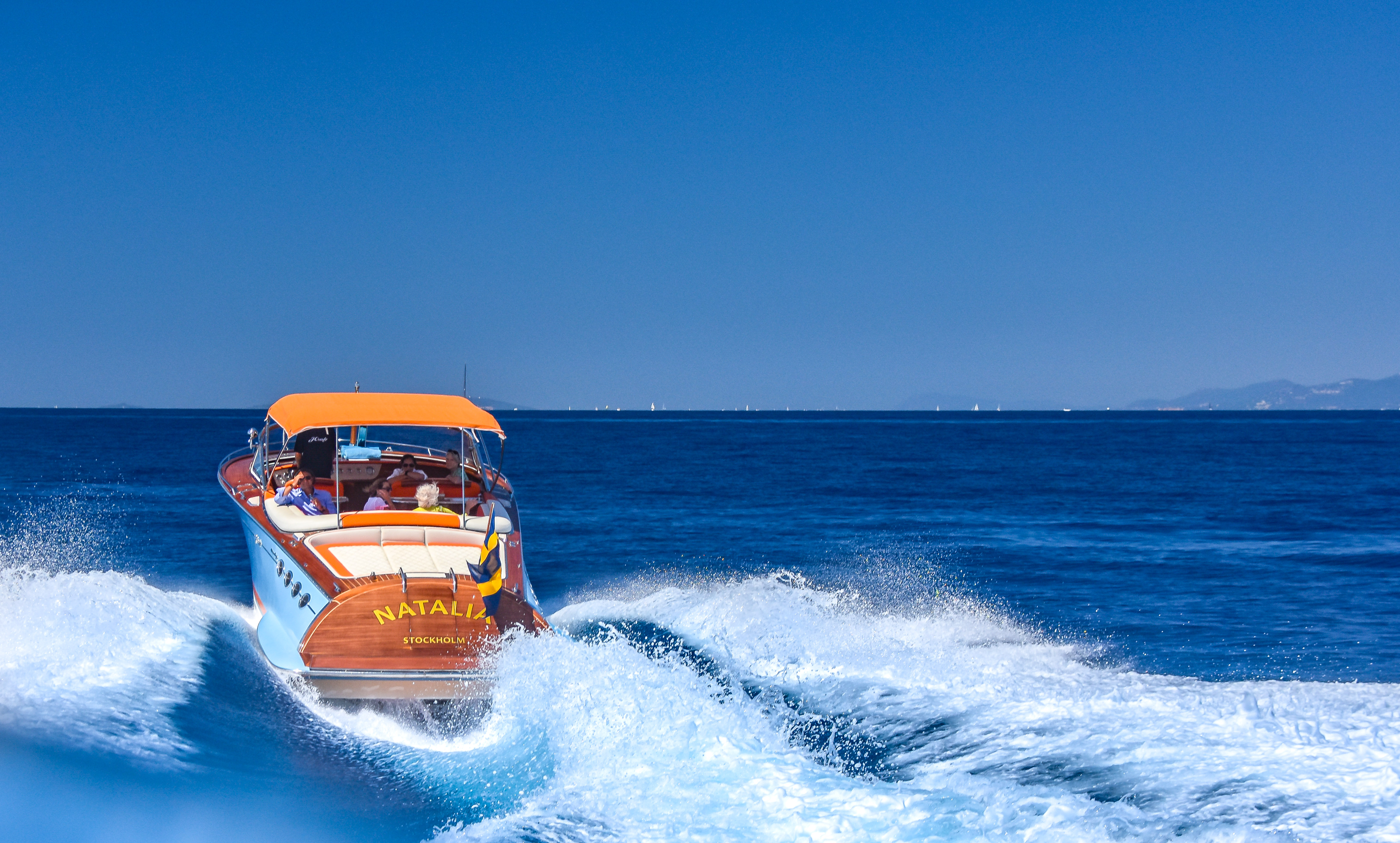 J Craft Torpedo Natalia from Stockholm at speed on deep blue water, dramatic white wake on a clear sunny day