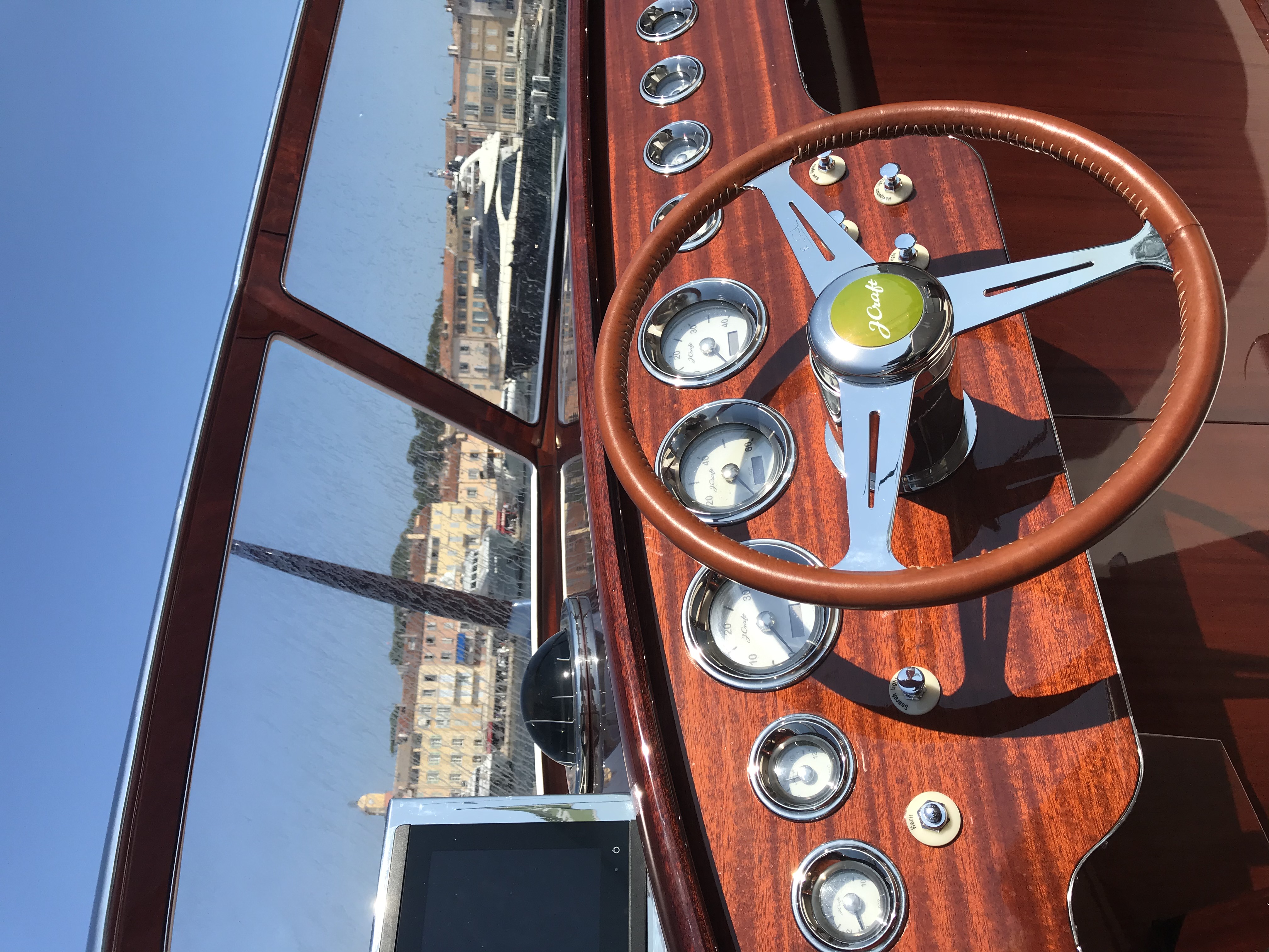 J Craft helm from captain's perspective with mahogany dashboard and harbor visible through windscreen