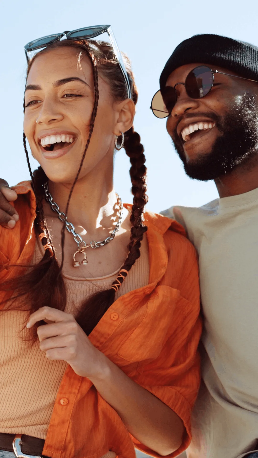A woman and a man with different hairstyles are sitting next to each other, smiling.