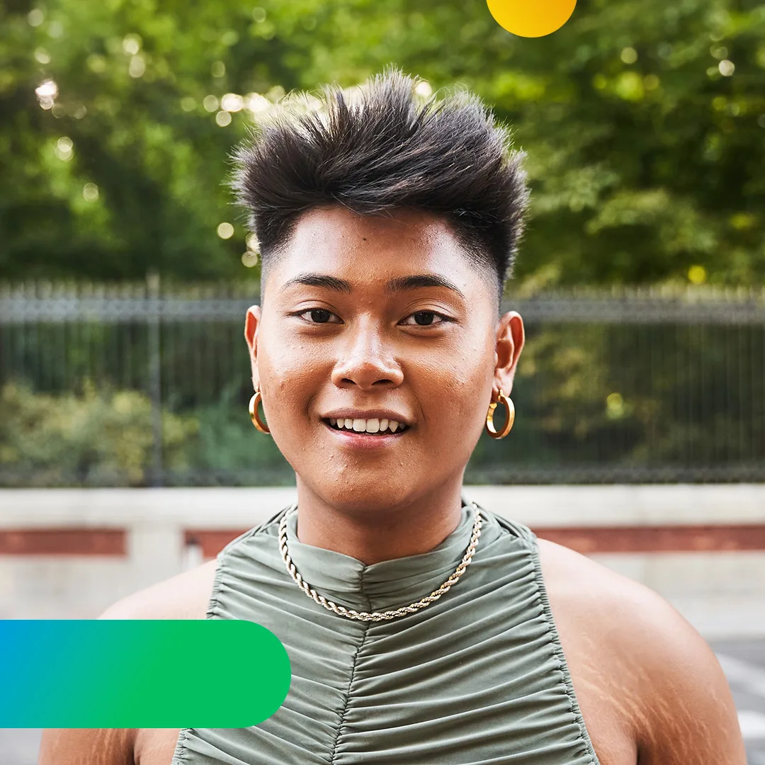 A woman with short hair and gold earrings against a green background.