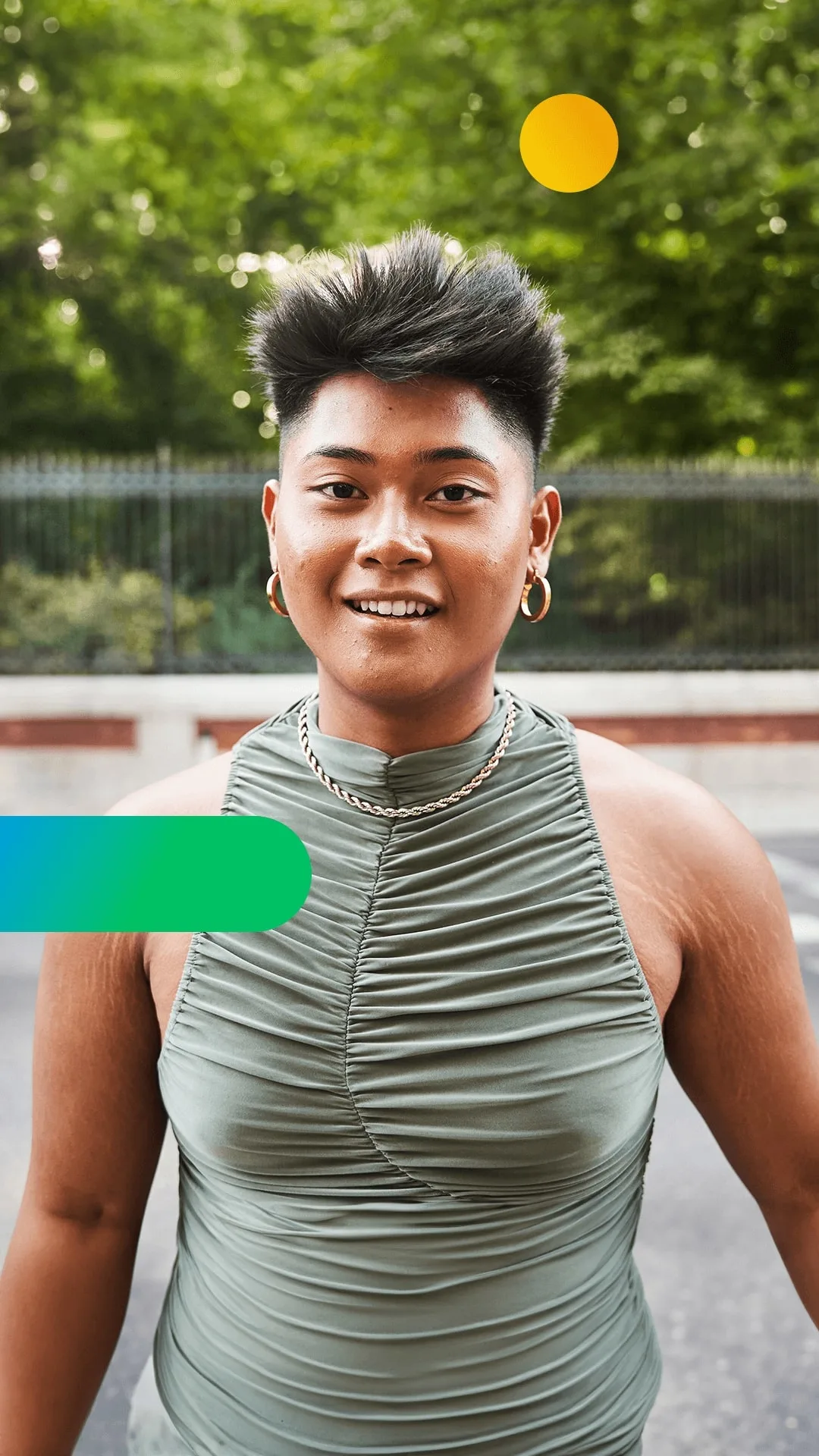 A woman with short hair and gold earrings against a green background.