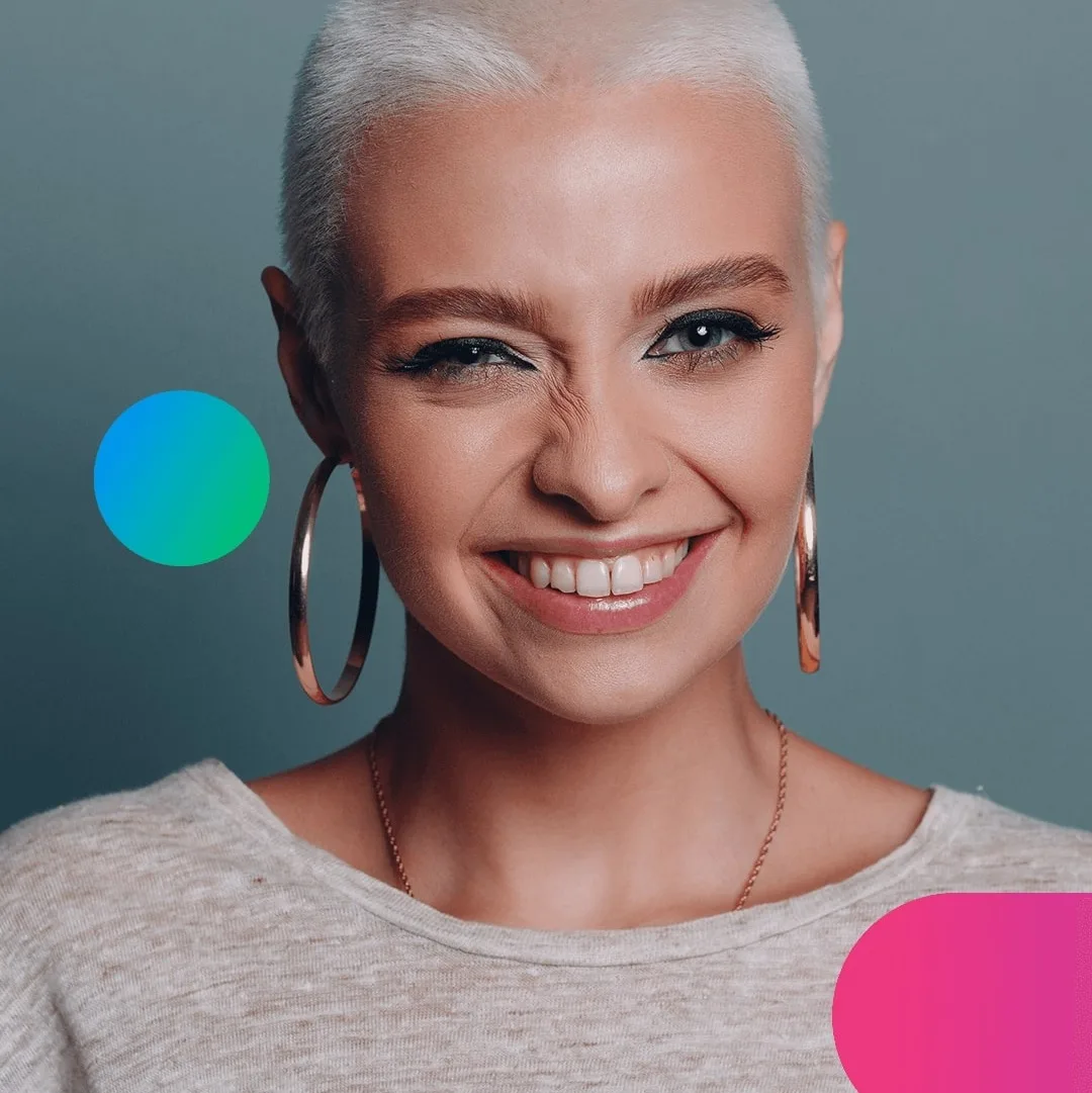 A woman with short blonde hair, wearing large hoop earrings, smiles broadly.