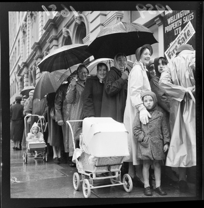 Vintage photo of large crowd queuing in the rain with umbrellas