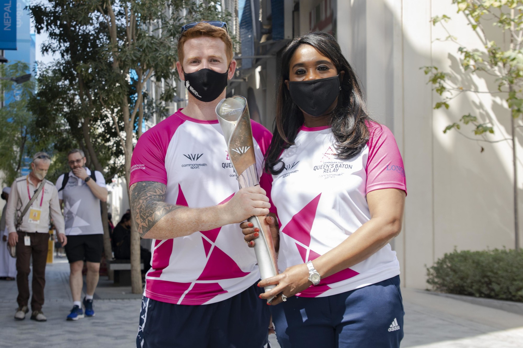 James Simpson (L), hands over the baton to Tessa Sanderson (R), Baton Bearer at the Queen-s Baton Relay event outside the Barbados Pavilion during the United Kingdom National Day celebrations m46426