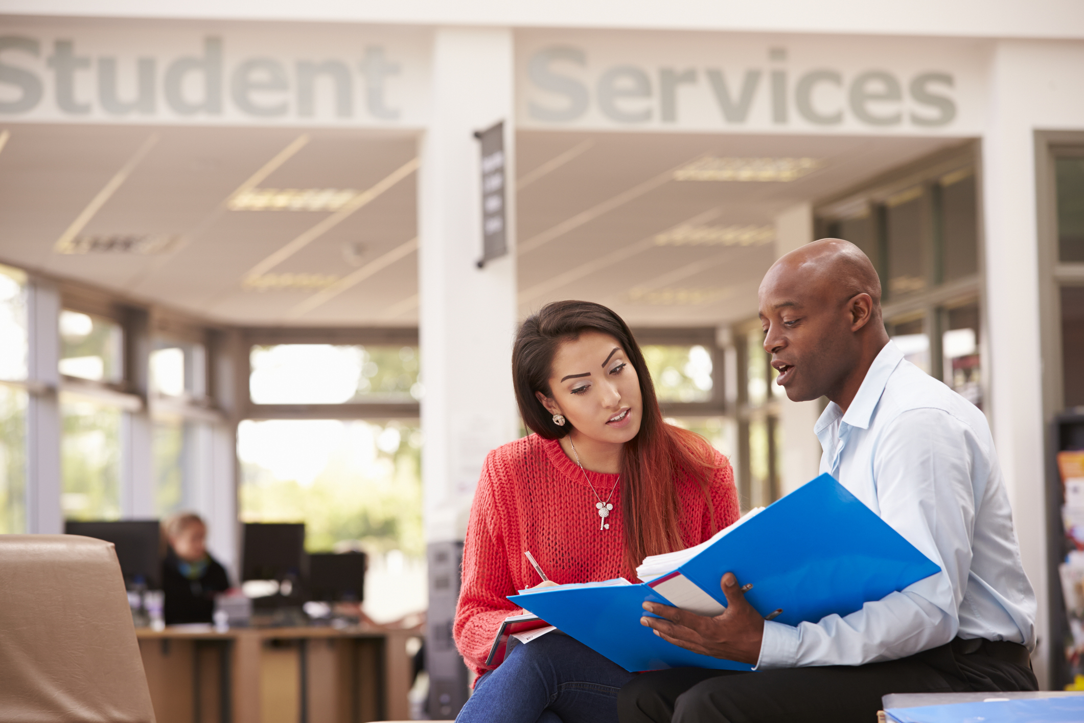 A mentor teacher sitting with a mentee teacher in a school