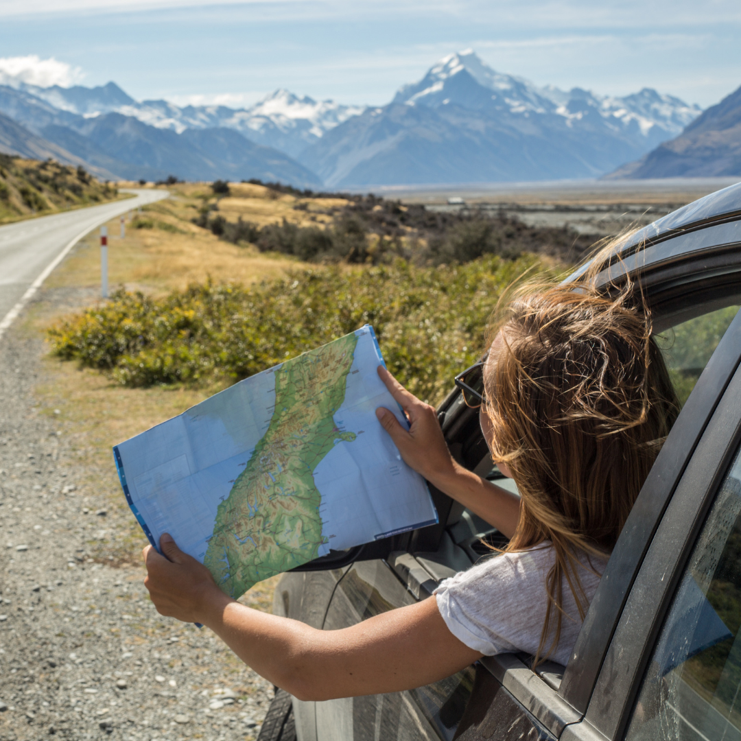 Girl in a car looking at a road map and the road ahead.