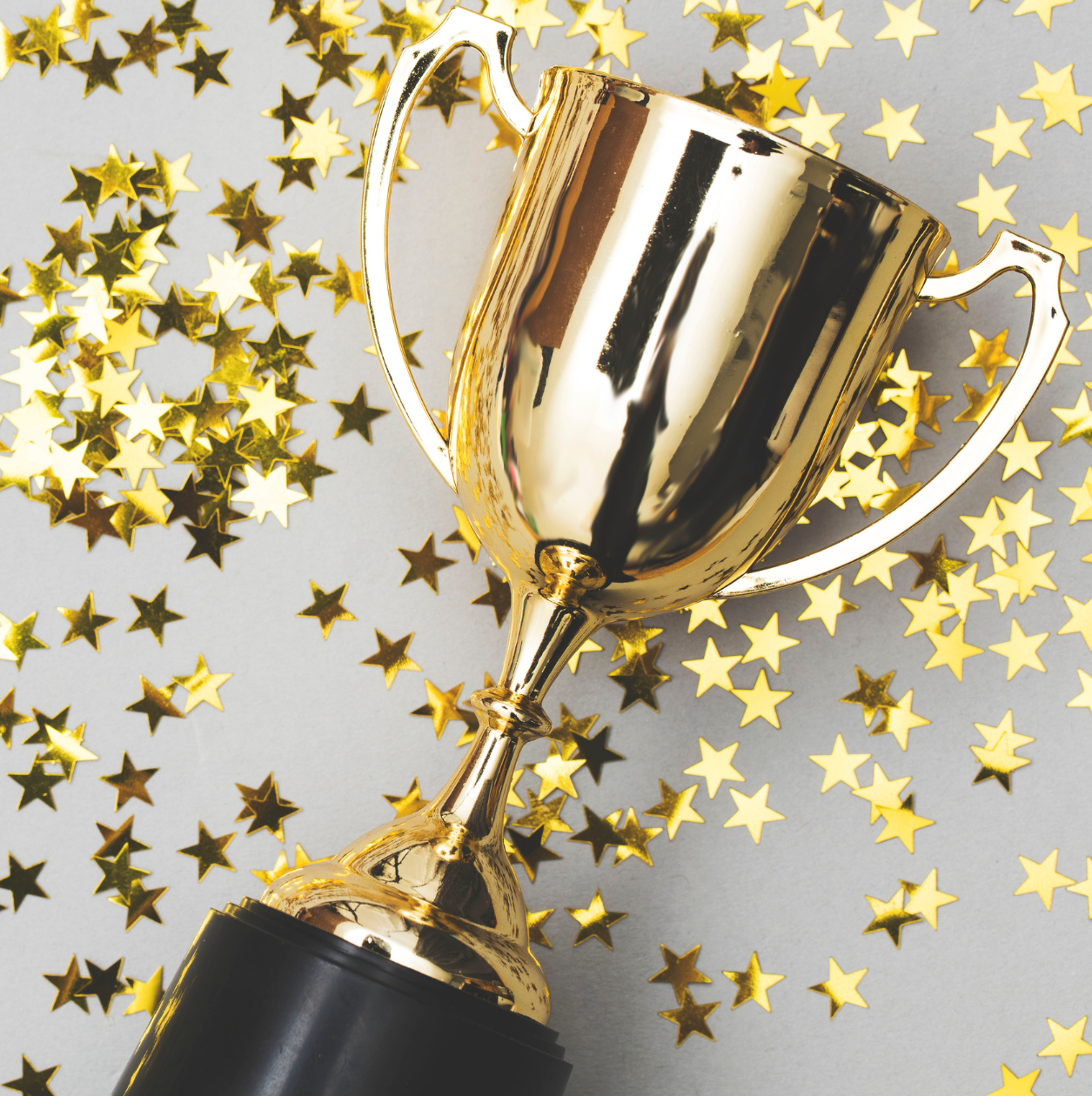 A gold trophy laying down amongst gold star stickers.