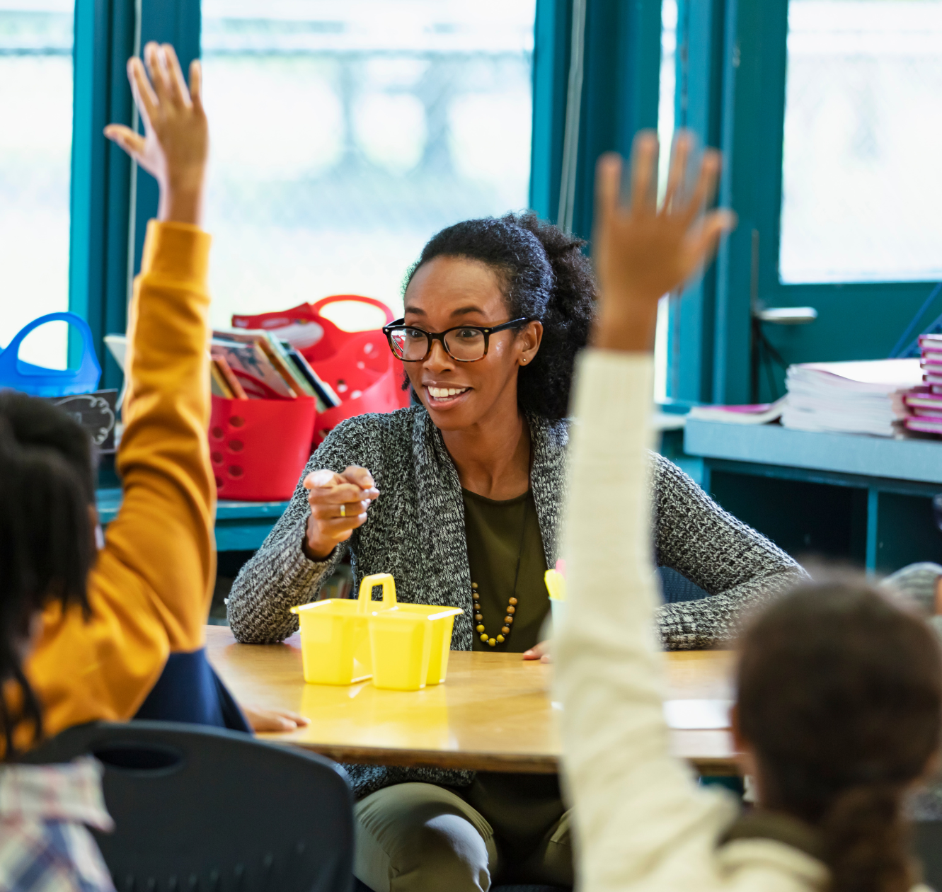 A young first-year teacher pointing into a crowd of students eagerly raising their hands.