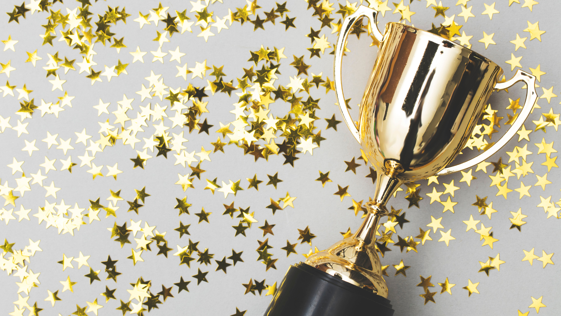 A gold trophy laying down amongst gold star stickers.