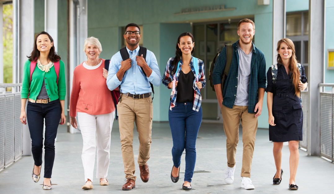 Six teachers ranging in age, race, and gender are walking through a school.