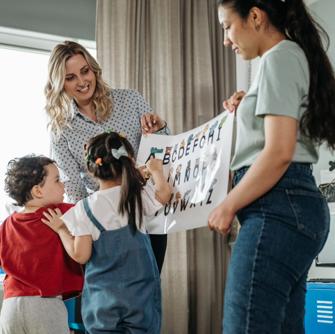 Mentor teacher co-teaching letter identification with a student teacher to two pre-school students.
