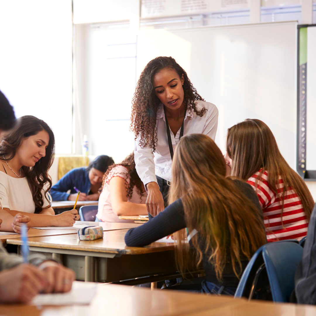 A student teacher is teaching a class while the mentor teacher observes her.