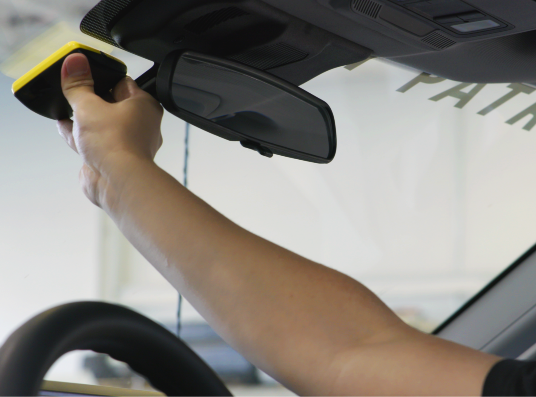 A man in a car placing a transponder on his windshield. 