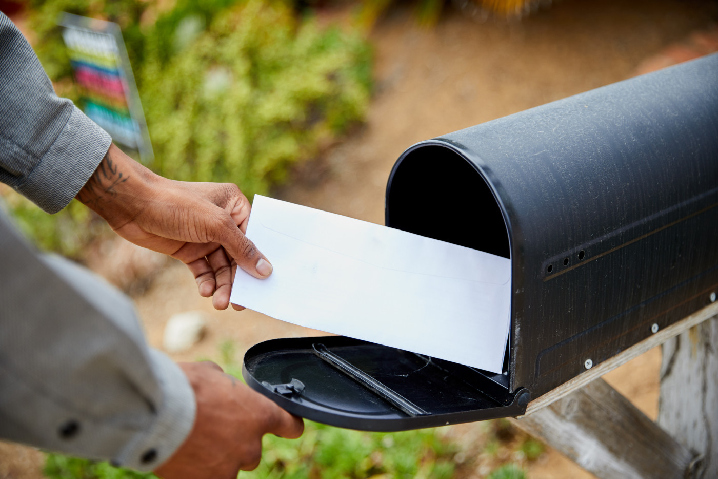 A person taking mail out of a black mailbox.