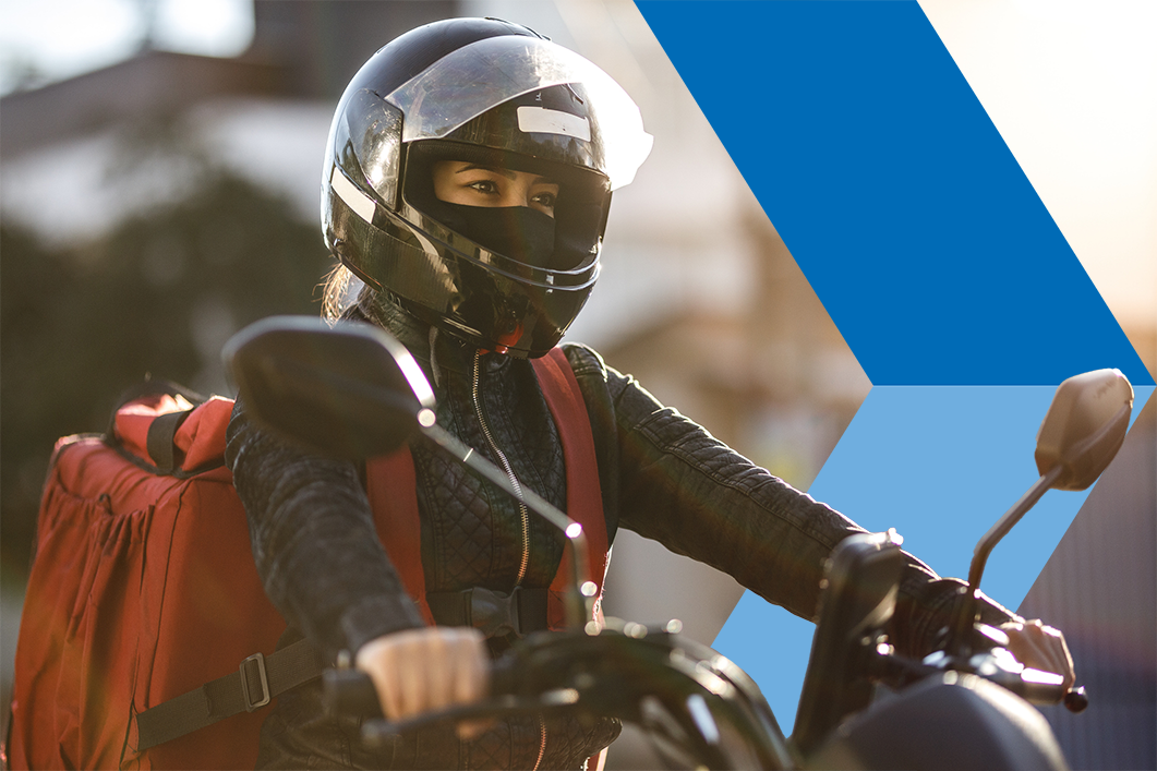 Woman on a motorcycle with a helmet and backpack.