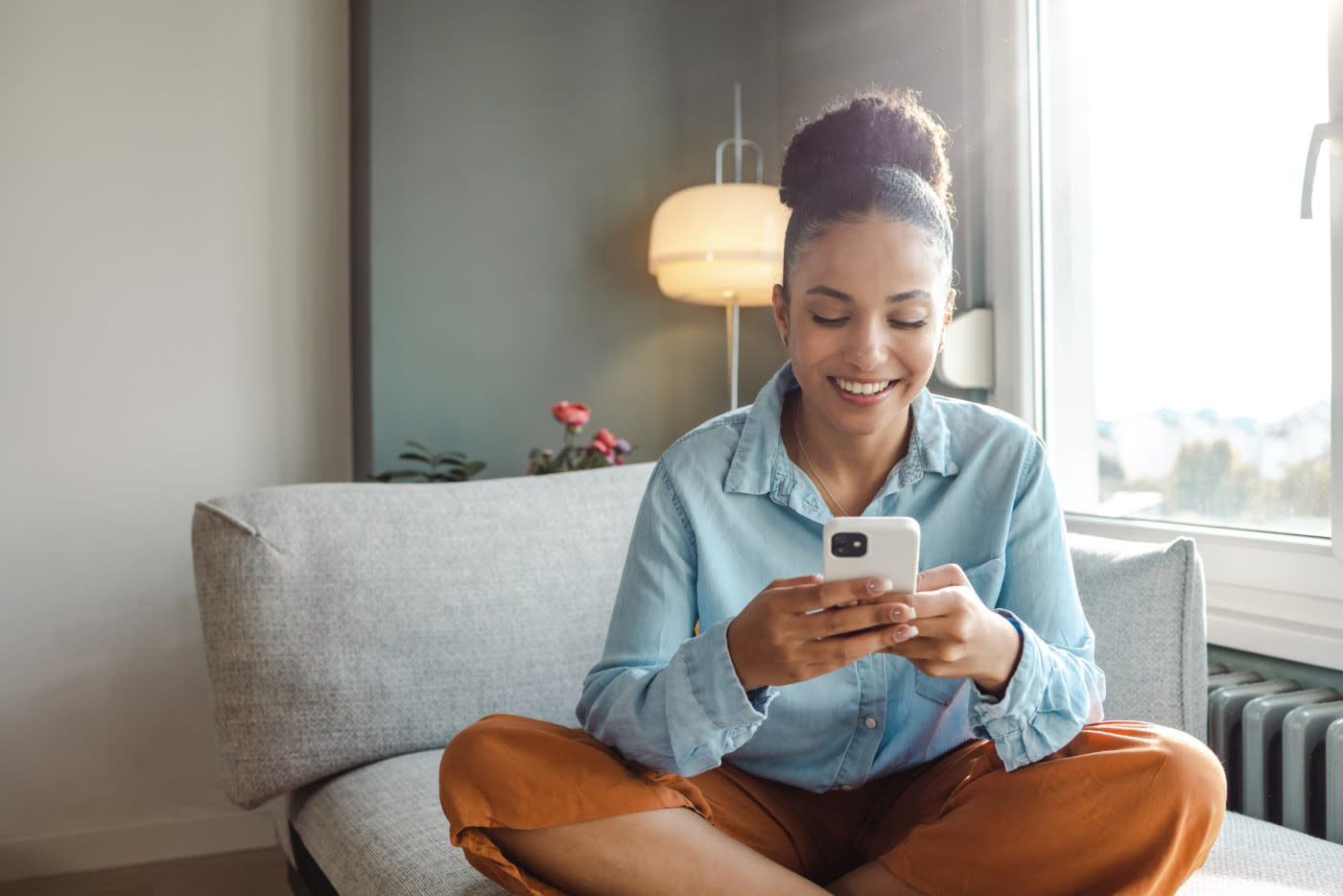 A woman sitting on a couch on her phone.