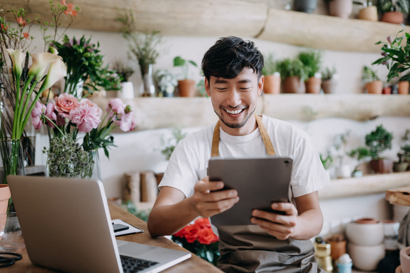 A man in a flower shop looking at a tablet.