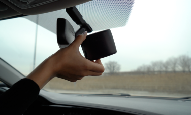 A person installing a 407 ETR transponder in their car.