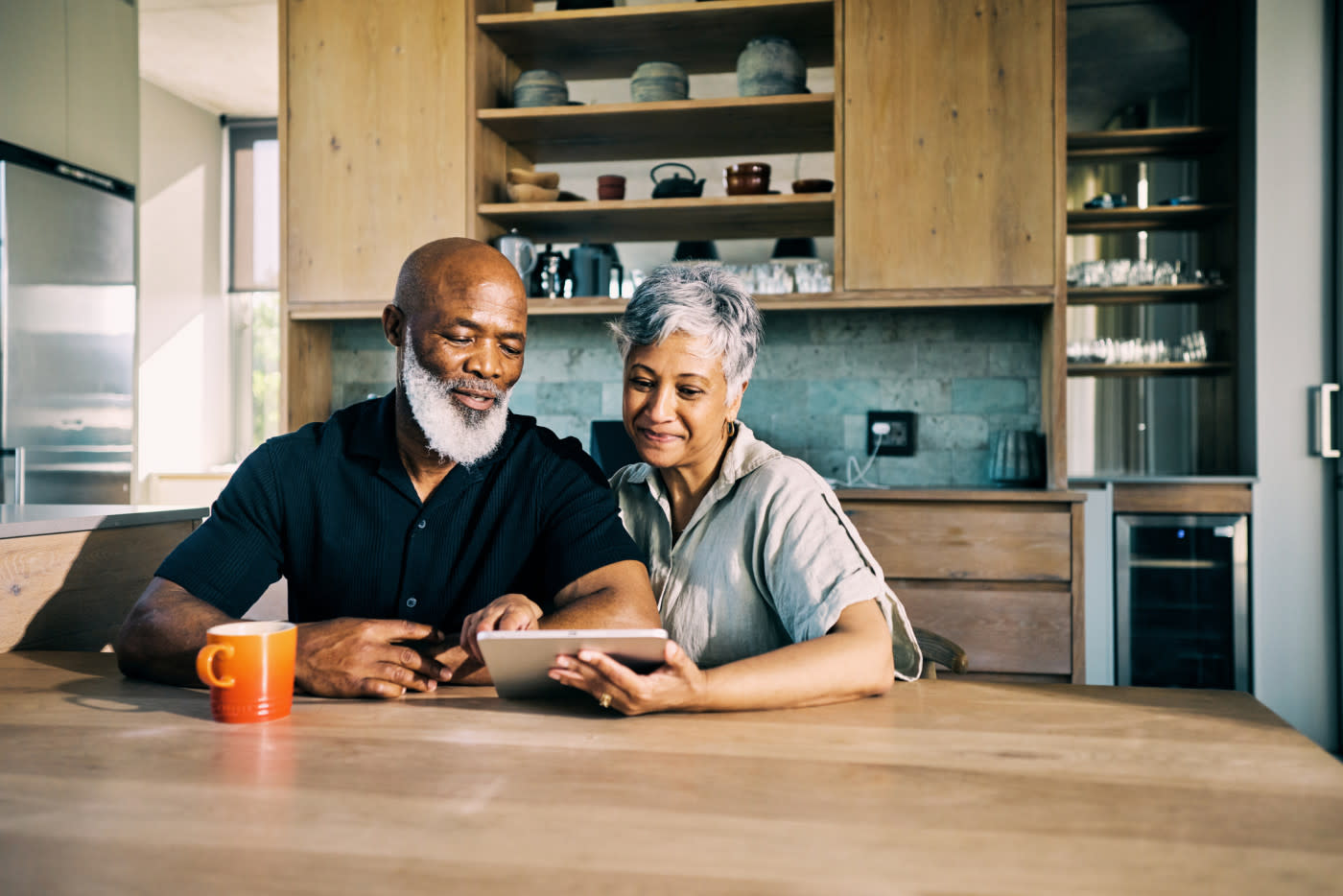 Two people smiling in front of a tablet.