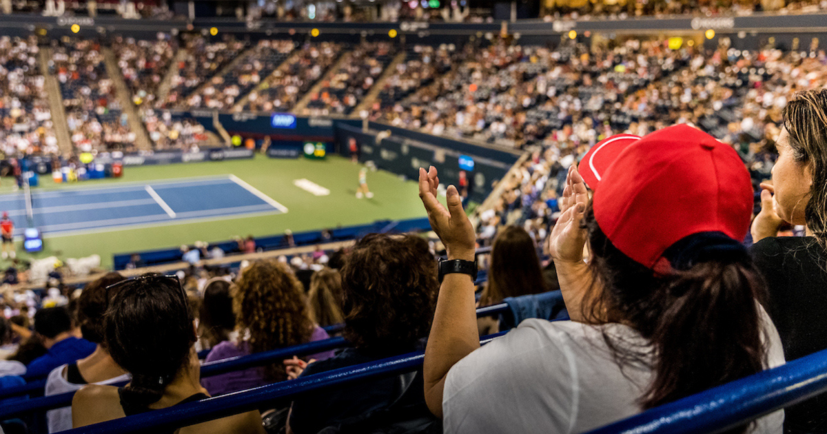 person in red hat watching tennis match