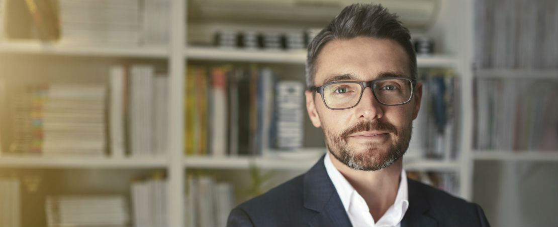 Man in business attire with glasses staring at camera