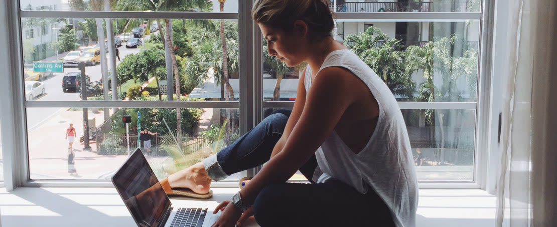 Woman sitting near windows looking at laptop