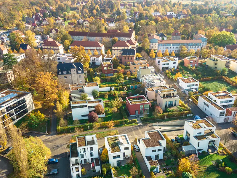 Luftbild einer Vorstadt. Es sind Häuser mit Flachdächern und Steildächern zu sehen.