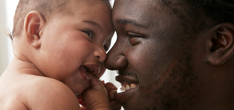 dad holding baby smiling