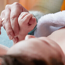 Baby in towel holding mother hand