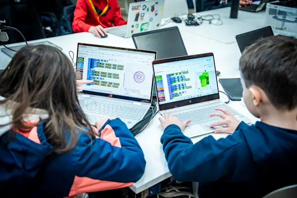 Two young people and their block code on laptops during a Code Club session.