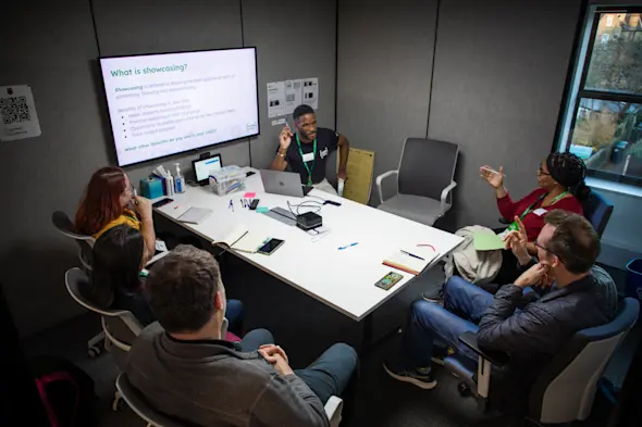 Participants at Clubs Con 2024 sit around a table discussing showcasing.
