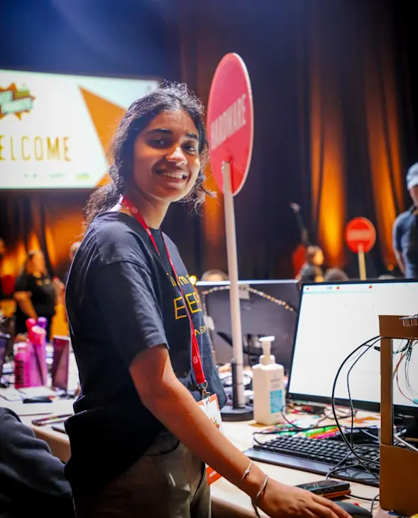 A smiling young person presents a tech creation at Coolest Projects.