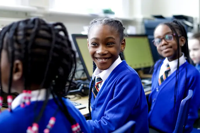 Smiling kids in a computing classroom.