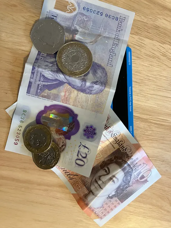 A photograph of UK cash and a bank card underneath.