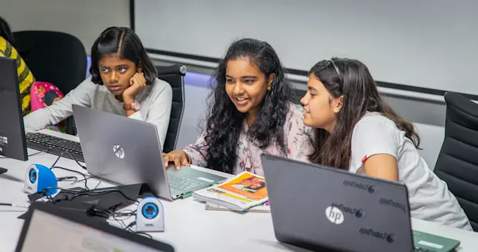 Three young people enjoy a coding club session.