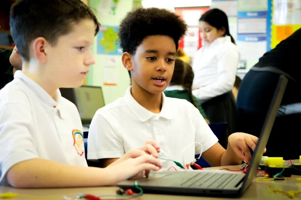 Two learners in a computing lesson at a laptop.