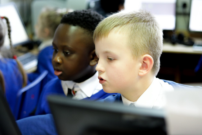 Two primary-aged children working together at a computer