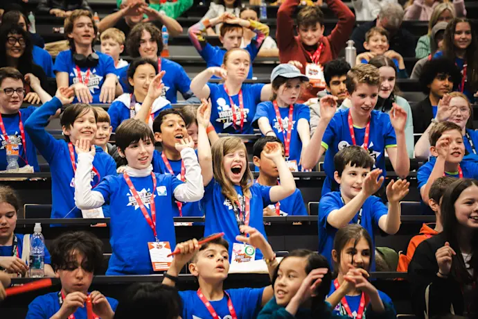 A crowd of young people celebrates in an auditorium.