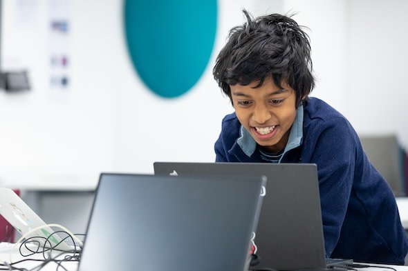 Smiling learner in classroom at computer.