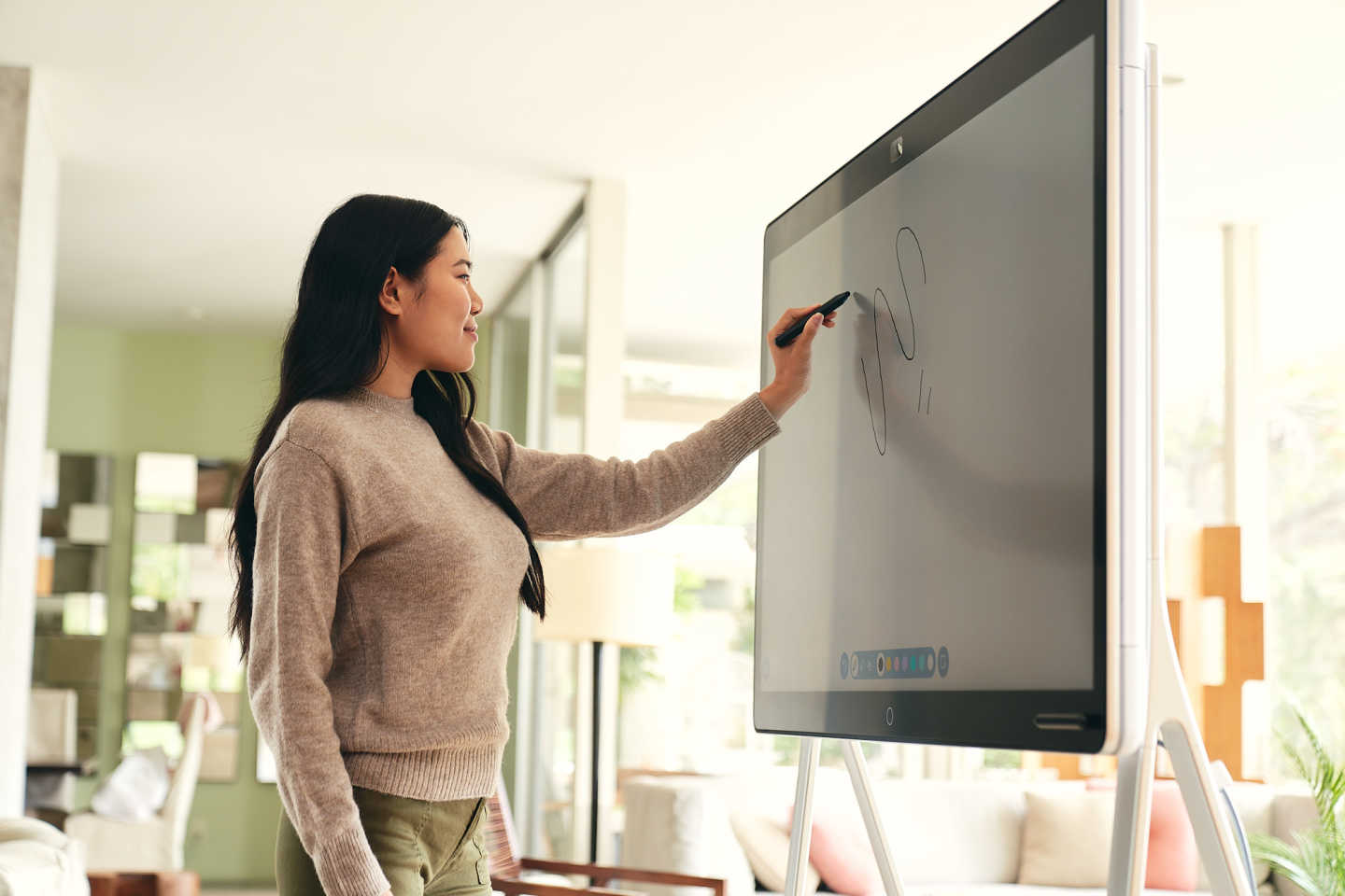 Woman smiling and drawing with a stylus on a Webex Board device with a floor stand