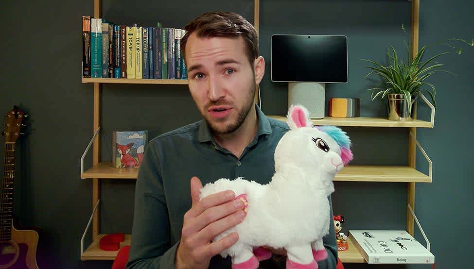 Man sitting in living room facing the camera, holding a toy